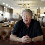 still from video featuring Norm sitting in booth being interviewed